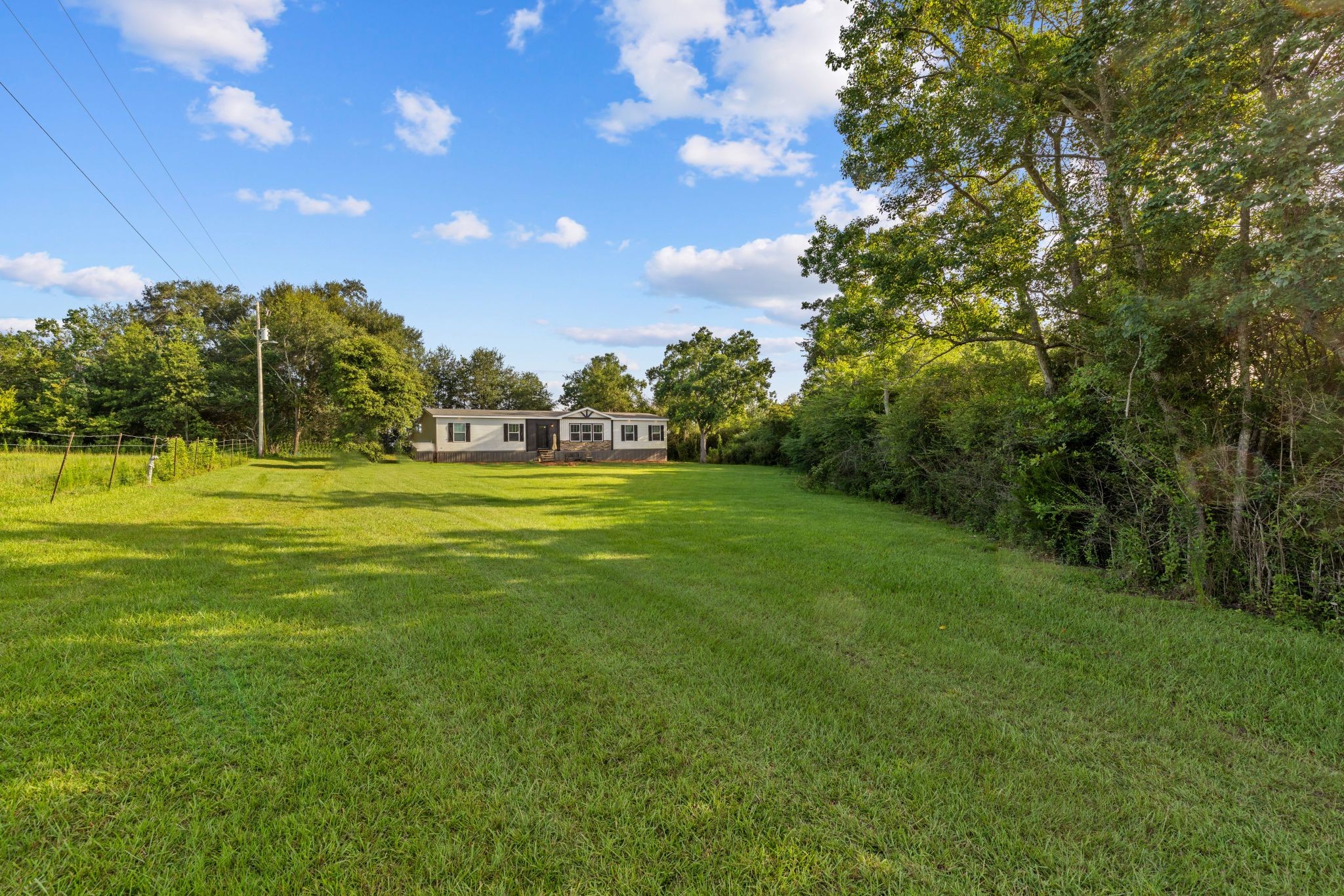 Home across a wide open lawn under a clear sky
